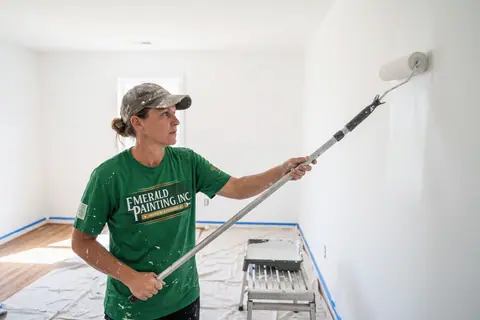 A house painter rolling a fresh coat onto an interior wall