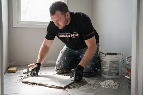 A tile installer setting a large floor tile in a bathroom