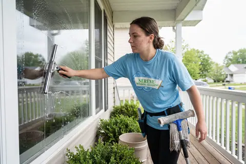 A window cleaner using a squeegee on a residential window