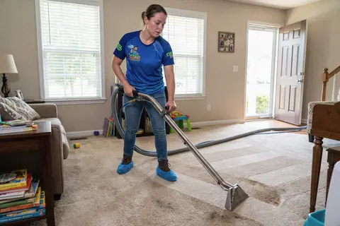 A carpet-cleaning professional using an extractor in a living room