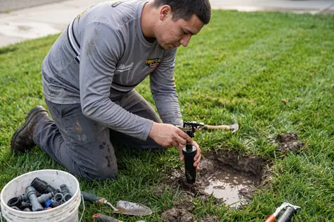 An irrigation technician setting a new sprinkler head in the lawn
