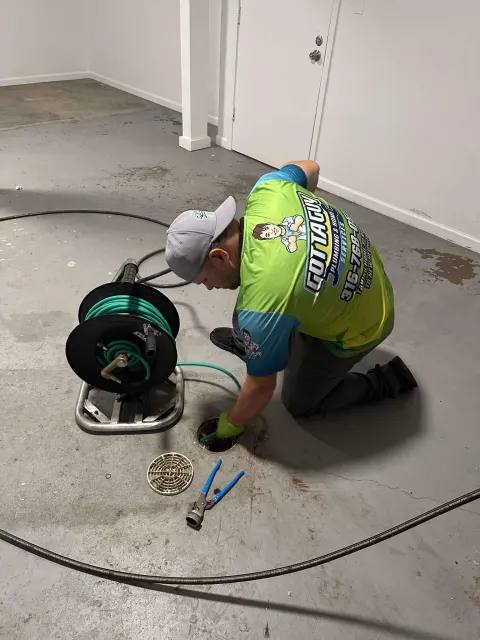 A plumber clearing a floor drain with a cable machine