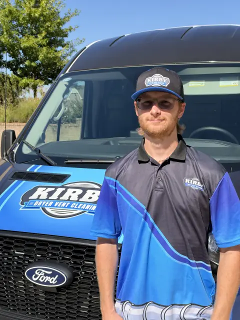 A Kirby Dryer Vent Cleaning professional standing beside his service van