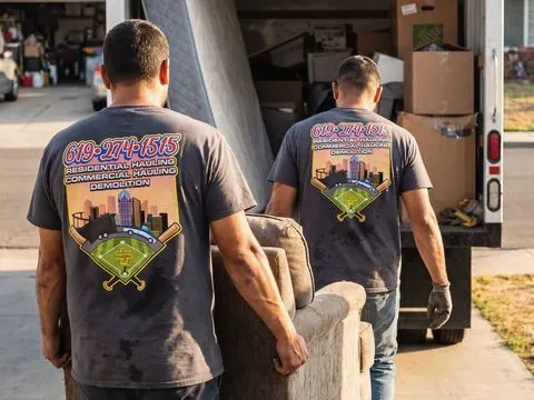 The crew carrying an armchair down the driveway to the truck.